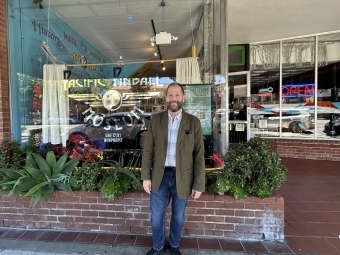 a man stands in front of a pinball museum smiling