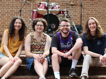 a group of students in a band sit on a stage together outside