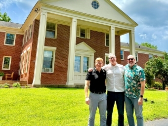 a group of three professors in front of a church on a sunny day