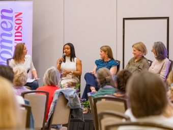 Women holding microphone onstage at conference
