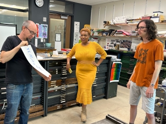 Three people in the letterpress lab, looking at a print