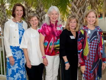 Five women stand outdoors wearing nametags