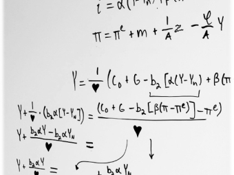 A whiteboard contains handwritten macroeconomic algebraic derivations for output (Y), interest rates (i), and inflation (π), using a heart symbol as a placeholder for a specific multiplier term.