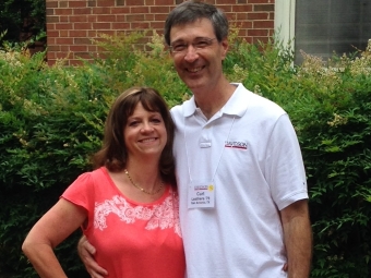 A woman in a pink shirt and white leggings poses with a man in a white polo outdoors