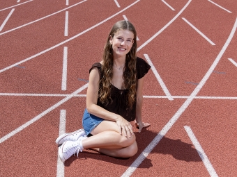 A young woman with long brown hair on a track field