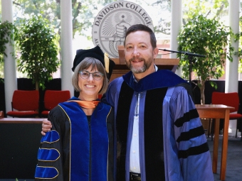 Two faculty members smile at commencement