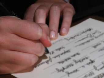 A pair of caucasian hands holding a pen write a signature