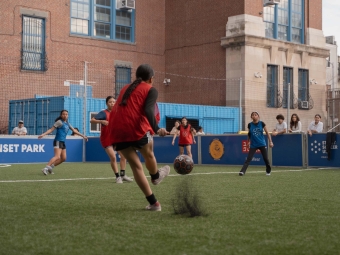 A group of boys and girls playing soccer in red and blue team jerseys