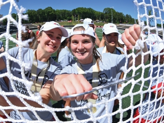 Davidson women’s lacrosse team peek through nettings. They won the 2026 A10 Conference championship