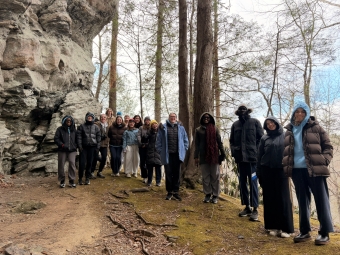 A group of students on a mossy mountainside, in warm clothing