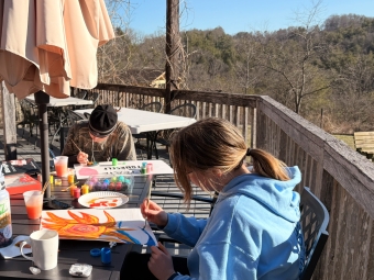 Two students sit outdoors painting