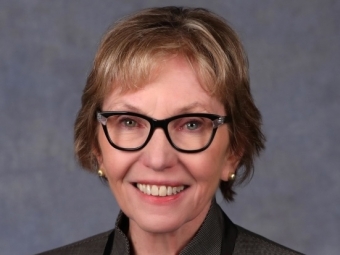 A white woman with blonde short hair and dark rimmed glasses