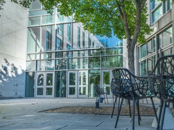 Wall Academic Center photo taken from the Mauze entrance with class walls, trees, metal seats and pavers
