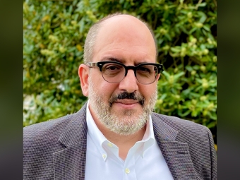Headshot of a professor with glasses, facial hair, and a blazer