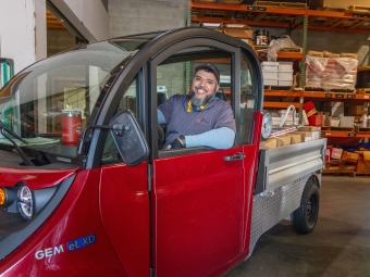 Physical Plant employee in the delivery truck with packages in the bed of the truck