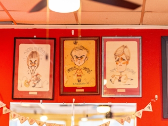 Three drawn portraits on a red wall 