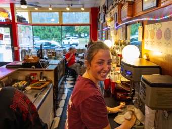 A person smiling while making a milkshake in an old soda shop