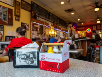 A napkin dispenser and a container of condiments on a table in a retro soda shop