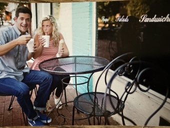 A young couple sipping milkshakes outside of a retro soda shop