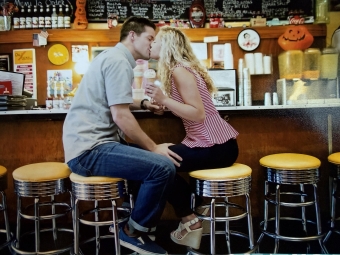 A young couple kissing at the bar in an old fashioned soda shop