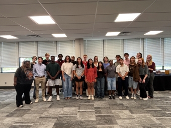 a group of students stand together in an office space smiling