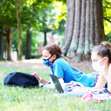 Students with masks on quads social distancing with laptops