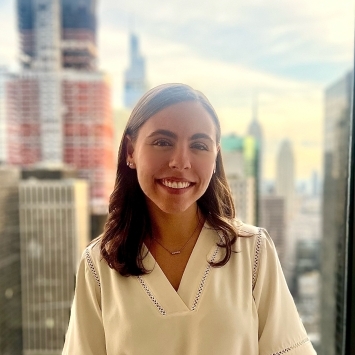 a young white woman smiles in front of a NYC skyline