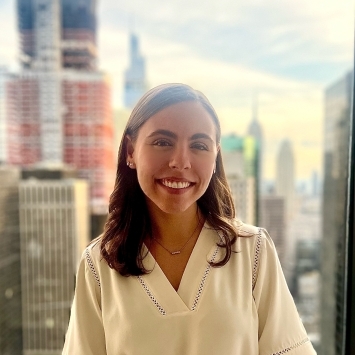 a young white woman smiles in front of a NYC skyline