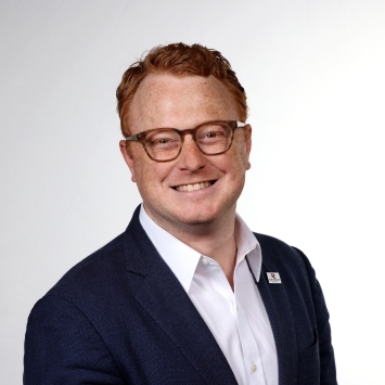 a young white man with red hair wearing glasses