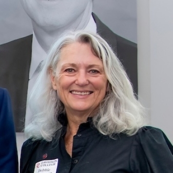a white woman with grey hair wearing a black top and smiling