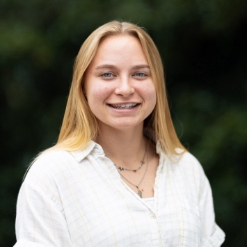a young white woman with blonde hair wearing a collared white shirt