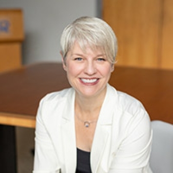 a middle aged white woman wearing a white blazer with white hair