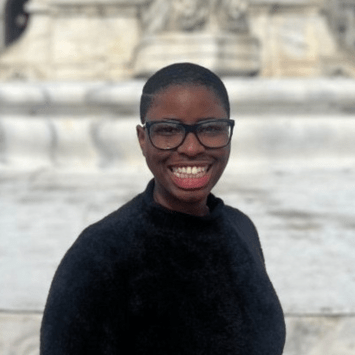 a young Black woman with glasses wearing a black top