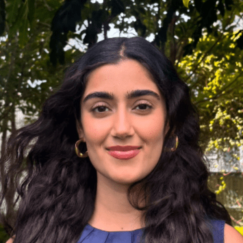 a young woman with long dark hair wearing gold earrings and a blue top