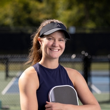 a young woman wearing a pickleball outfit and holding a paddle