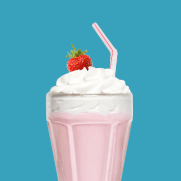 An old fashioned strawberry milkshake topped with whipped cream and striped straw on a blue background