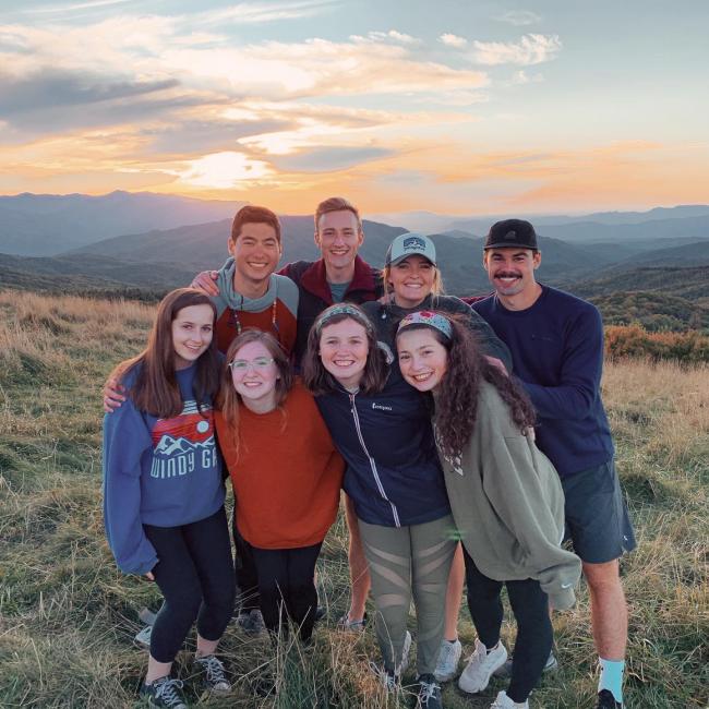 group poses for picture on the hills at sunset