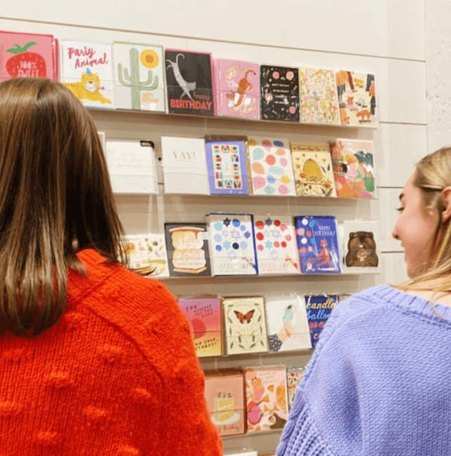 two young women look at a wall of cards