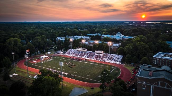 an aerial view of a football field and track at sunset