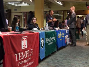 Rows of booths are visible at the law school fair with students talking to recruiters