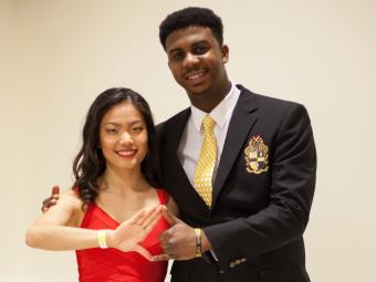 Two Students make Delta Sorority and Alpha Fraternity hand signs
