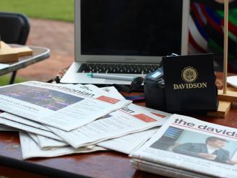 The Davidsonian copies on a table with a laptop and Davidson gear