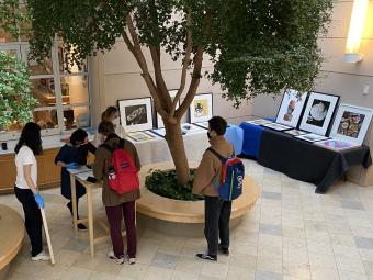 students around tables of artwork displayed