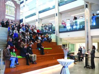 Carol Quillen addresses seated audience in atrium of Wall Center 